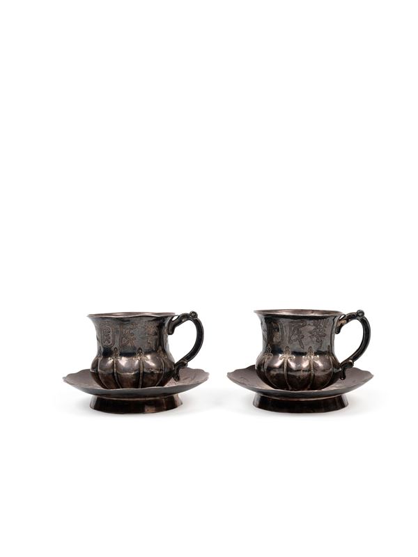 A PAIR OF SILVER CUPS WITH SAUCERS