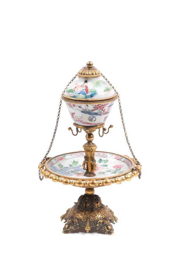 AN HORMOLU MOUNTED FAMILLE ROSE PORCELAIN CUP AND SAUCER