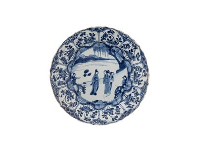 Cina, dinastia Qing (Kangxi), Piatto in porcellana bianca e blu a decoro figurato e cartigli